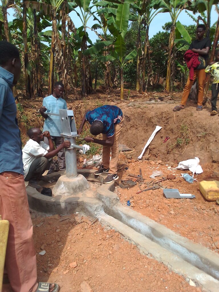 Men installing the pump handle on the water well.