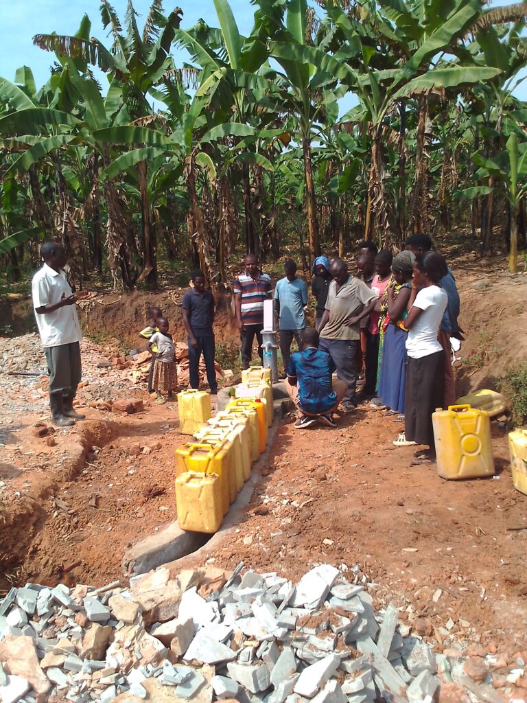 Pastor praying with community members at the newly commissioned water well.