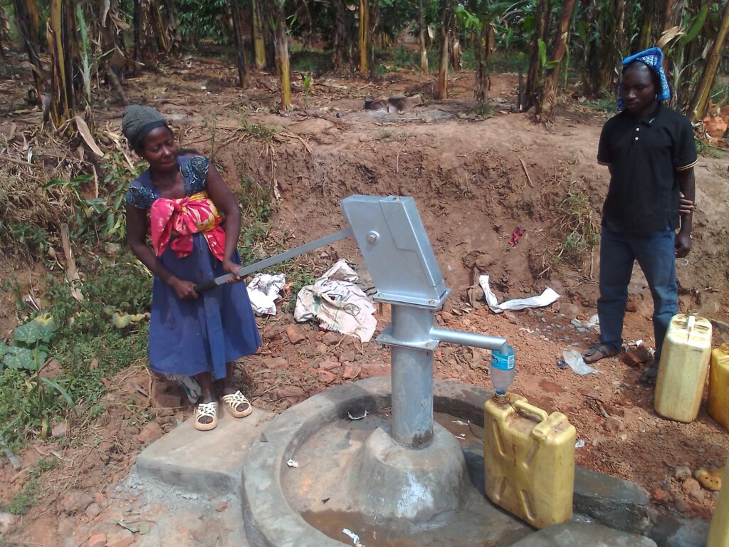 Woman pumping water from the new well while a man waits.